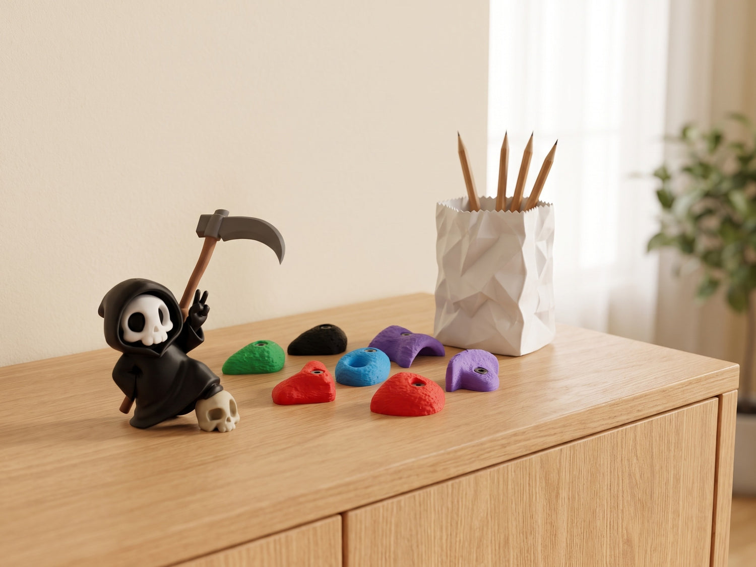 Sproutwerk Produktszene: Sensenmann-Figur, Bouldergriff-Magnete und Papiertüten-Stiftehalter auf einem Sideboard