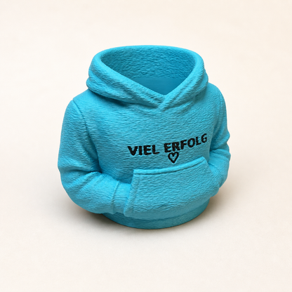Türkisfarbener personalisierter Hoodie-Stiftehalter mit Aufschrift „VIEL ERFOLG“ und Herz, 3D-gedruckt auf cremeweißem Hintergrund