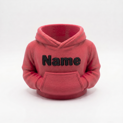 Rosafarbener Hoodie-Stiftehalter mit schwarzer Aufschrift Name auf weißem Studiohintergrund