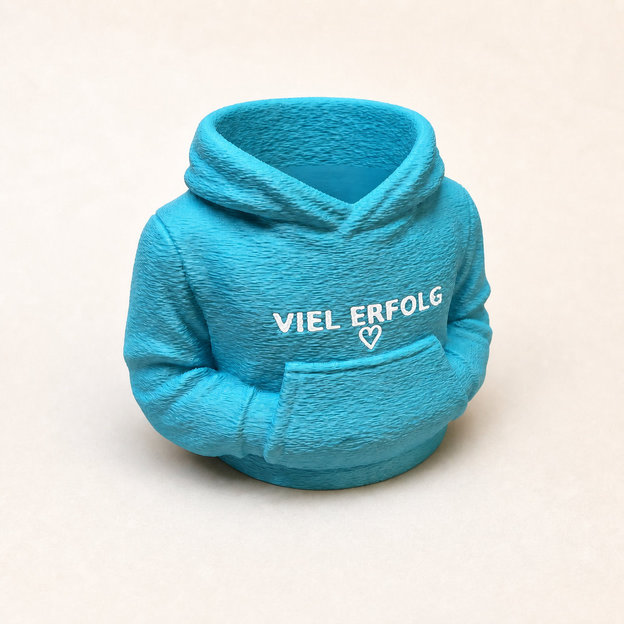 Türkisfarbener Hoodie-Stiftehalter mit weißer Aufschrift „VIEL ERFOLG“ und Herz auf cremeweißem Hintergrund