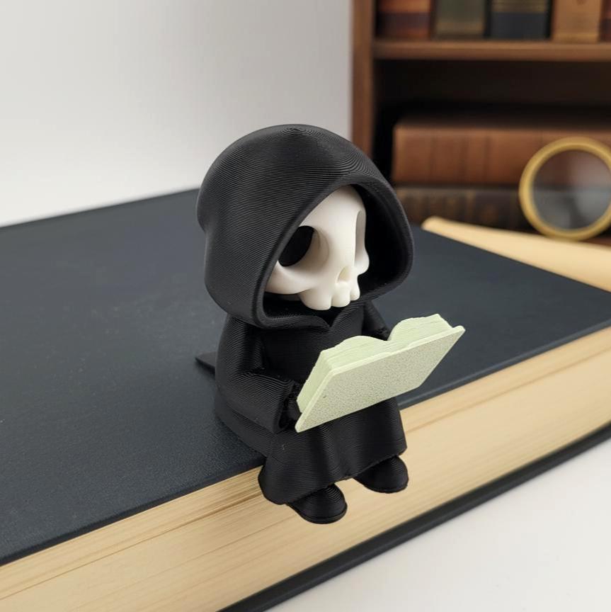 Lesender Sensenmann auf Buch – Detailansicht von Mantel und Schädel