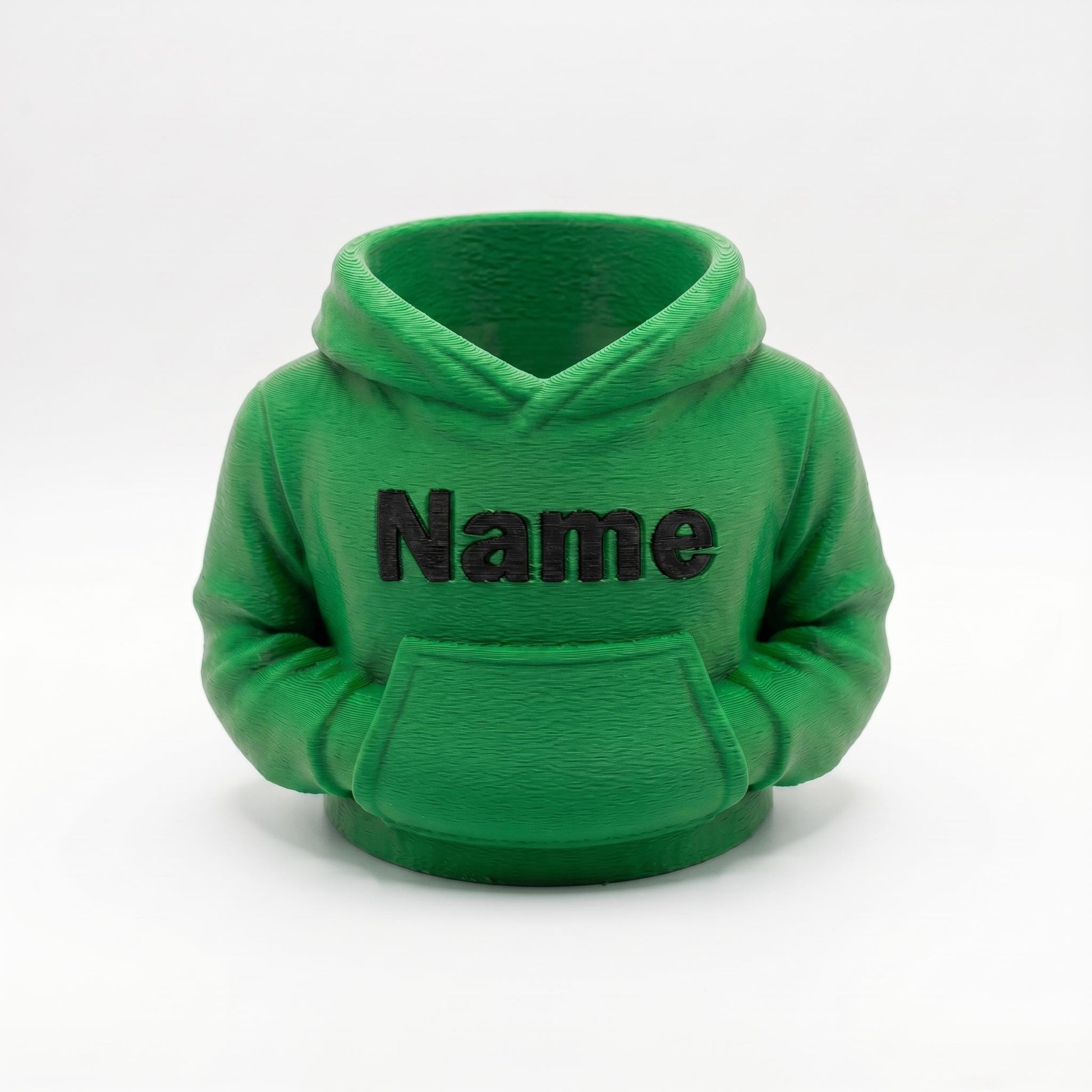 3D-gedruckter Stiftehalter in grüner Hoodie-Form mit schwarzem Name Schriftzug auf der Brust. Der detaillierte Organizer zeigt realistische Kapuze, Kängurutasche und Ärmel mit sichtbaren Drucklinien. Perfekt als Abschiedsgeschenk Lehrerin, Schulgeschenk oder Schreibtisch Organizer. Maße 11×10×7 cm, aus grünem PLA im 3D Druck hergestellt. Ideal für Einschulung oder als personalisierte Büro-Deko.