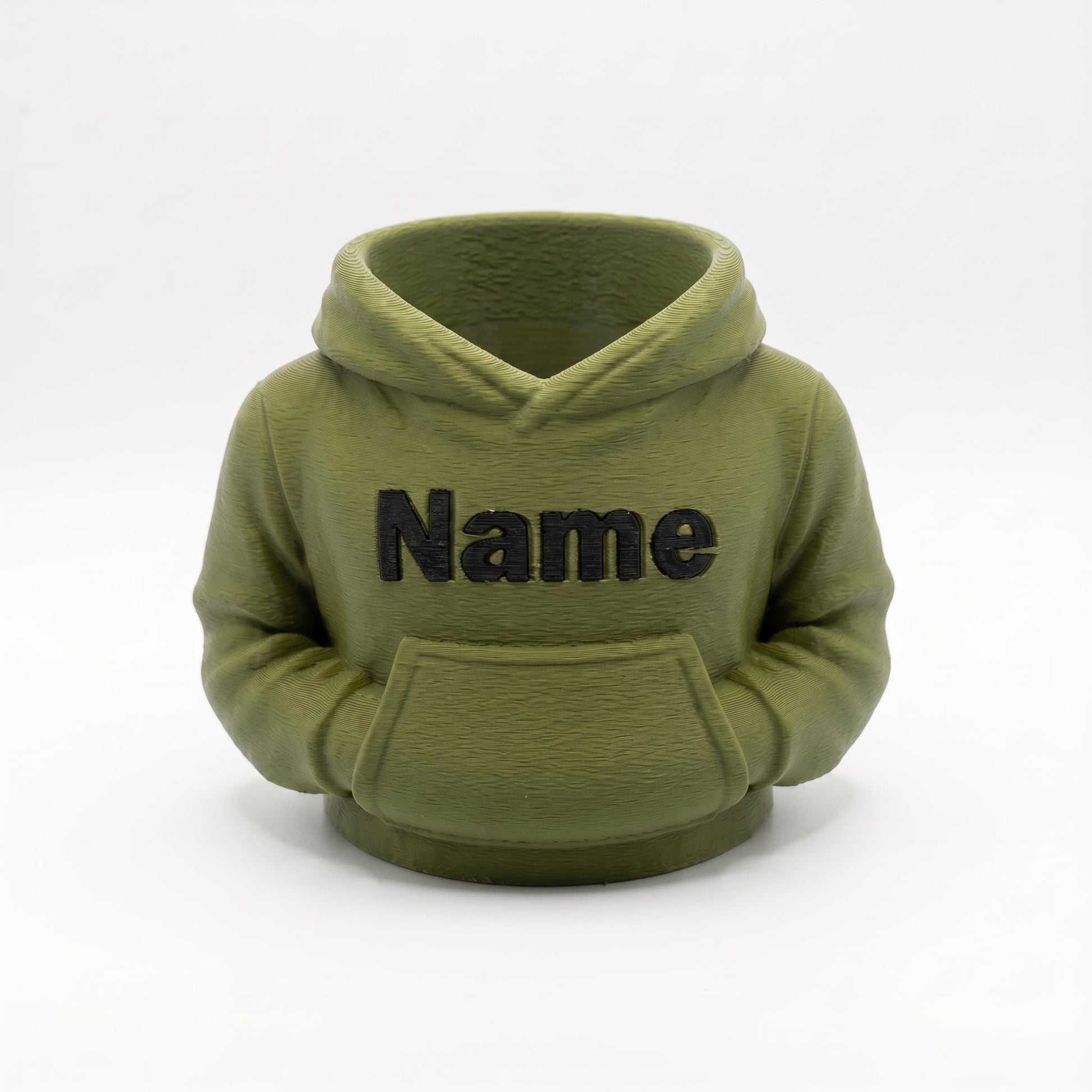 3D-gedruckter Stiftehalter in olivgrüner Farbe im niedlichen Hoodie-Design mit schwarzem Name Schriftzug auf der Vorderseite. Der Organizer verfügt über eine Kapuze und Bauchtasche für Stifte und Büroartikel. Perfekt als Abschiedsgeschenk Lehrerin oder Erzieherin, Schulgeschenk oder Schreibtisch Organizer. Personalisierbar mit Wunschname. Maße: 11x10x7cm, umweltfreundliches PLA Material. Ideal für Büro, Klassenzimmer oder Kinderzimmer.