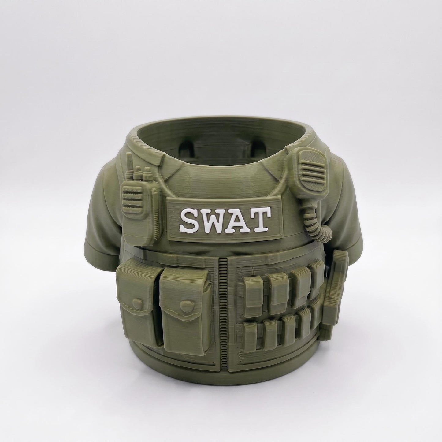 3D-gedruckter SWAT Stiftehalter in oliv-grüner Farbe mit detailgetreuen taktischen Elementen. Der runde Behälter zeigt eine realistische Schutzweste mit SWAT-Aufschrift, Ausrüstungstaschen, Funkgerät und Patronengurt. Perfekter Schreibtisch Organizer aus robustem PLA-Material. Ideales Abschiedsgeschenk für Lehrerin oder Erzieherin, auch als Schulgeschenk oder Mitgebsel geeignet. Maße: 11×10×7 cm, ca. 90g schwer.