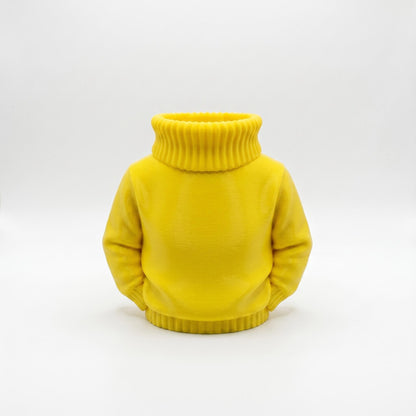 Ein gelber 3D-gedruckter Stiftehalter in Form eines Rollkragenpullovers ohne Kopf steht auf weißem Hintergrund. Der kompakte Organizer aus PLA-Material zeigt realistische Strickoptik mit geripptem Rollkragen und Bündchen am unteren Saum. Die glatte gelbe Oberfläche imitiert einen oversized Pullover perfekt. Ideal als Abschiedsgeschenk Lehrerin, Schulgeschenk oder Desk Organizer für den Schreibtisch. Maße 11x10x7 cm.
