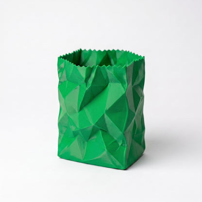 Moderner Stiftehalter in knallgrüner Farbe mit geometrischem zerknülltem Papiertüten-Design. Das 3D-gedruckte PLA-Objekt zeigt facettierte Oberflächenstruktur mit scharfen Kanten und Falten, die eine realistische zerknitterte Optik erzeugen. Perfekter desk organizer für Stifte und Bürozubehör. Maße 10x7x7cm, ideal als Schulgeschenk oder office desk decor. Hochwertige 3D-Druck-Qualität mit matter Oberfläche.