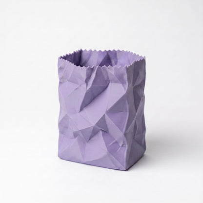 Ein lila Stiftehalter in zerknitterter Papiertüten-Optik steht vor weißem Hintergrund. Das 3D-gedruckte Design zeigt realistische Falten und Knicke einer zusammengedrückten Papiertüte. Der moderne desk organizer mit matter Oberfläche eignet sich perfekt als pen holder für den Schreibtisch oder als originelles Schulgeschenk.