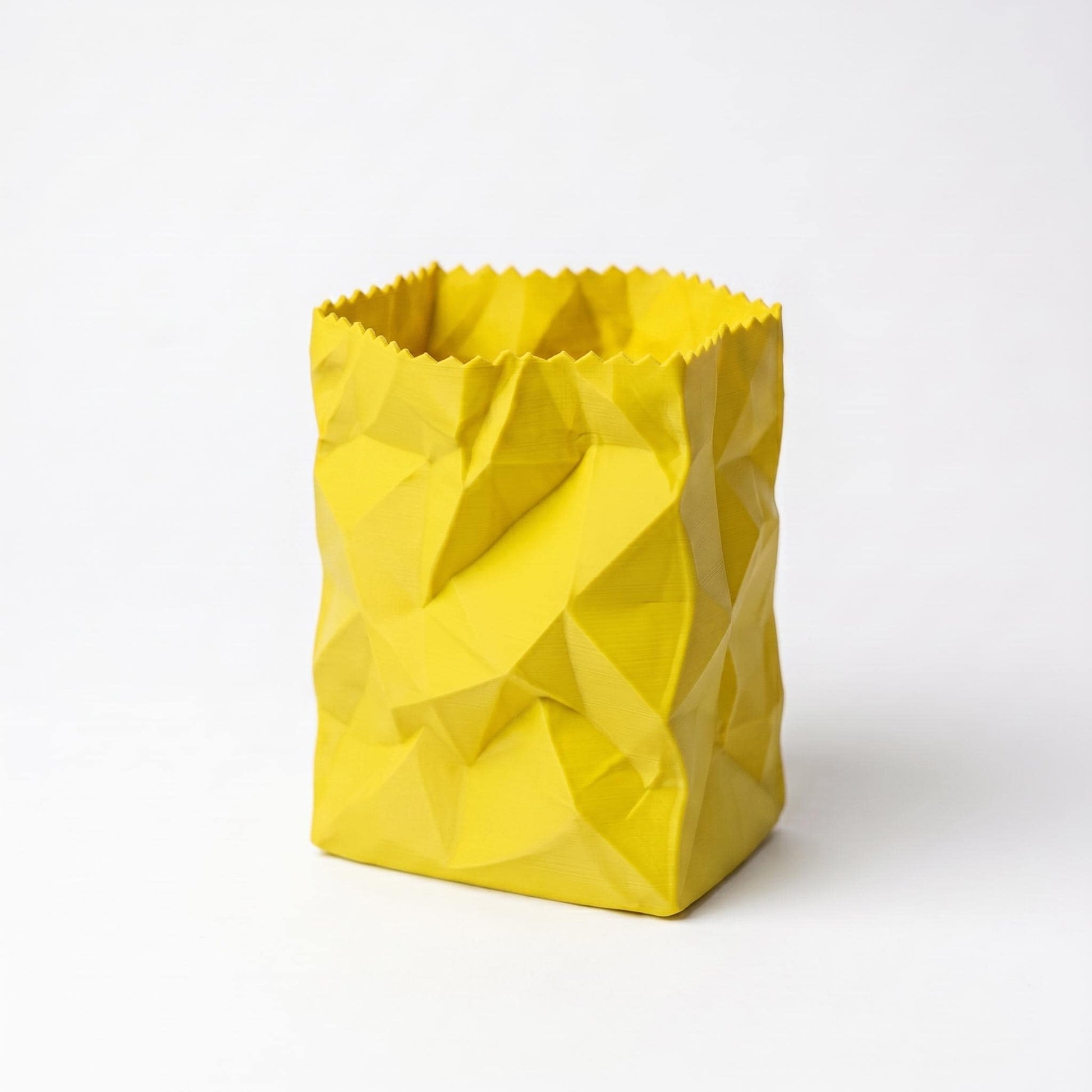 Gelber 3D-gedruckter Stiftehalter in zerknitterter Papiertüten-Optik mit geometrischen Falten und gezacktem oberen Rand. Das moderne Design verleiht jedem Schreibtisch eine spielerische Note. Perfekter desk organizer für Stifte und Büromaterial - ein echter Hingucker als office desk decor. Hochwertig aus PLA gefertigt, 10x7x7cm, in 9 Farben erhältlich.