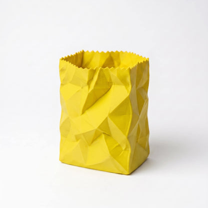 Gelber 3D-gedruckter Stiftehalter in zerknitterter Papiertüten-Optik mit geometrischen Falten und gezacktem oberen Rand. Das moderne Design verleiht jedem Schreibtisch eine spielerische Note. Perfekter desk organizer für Stifte und Büromaterial - ein echter Hingucker als office desk decor. Hochwertig aus PLA gefertigt, 10x7x7cm, in 9 Farben erhältlich.