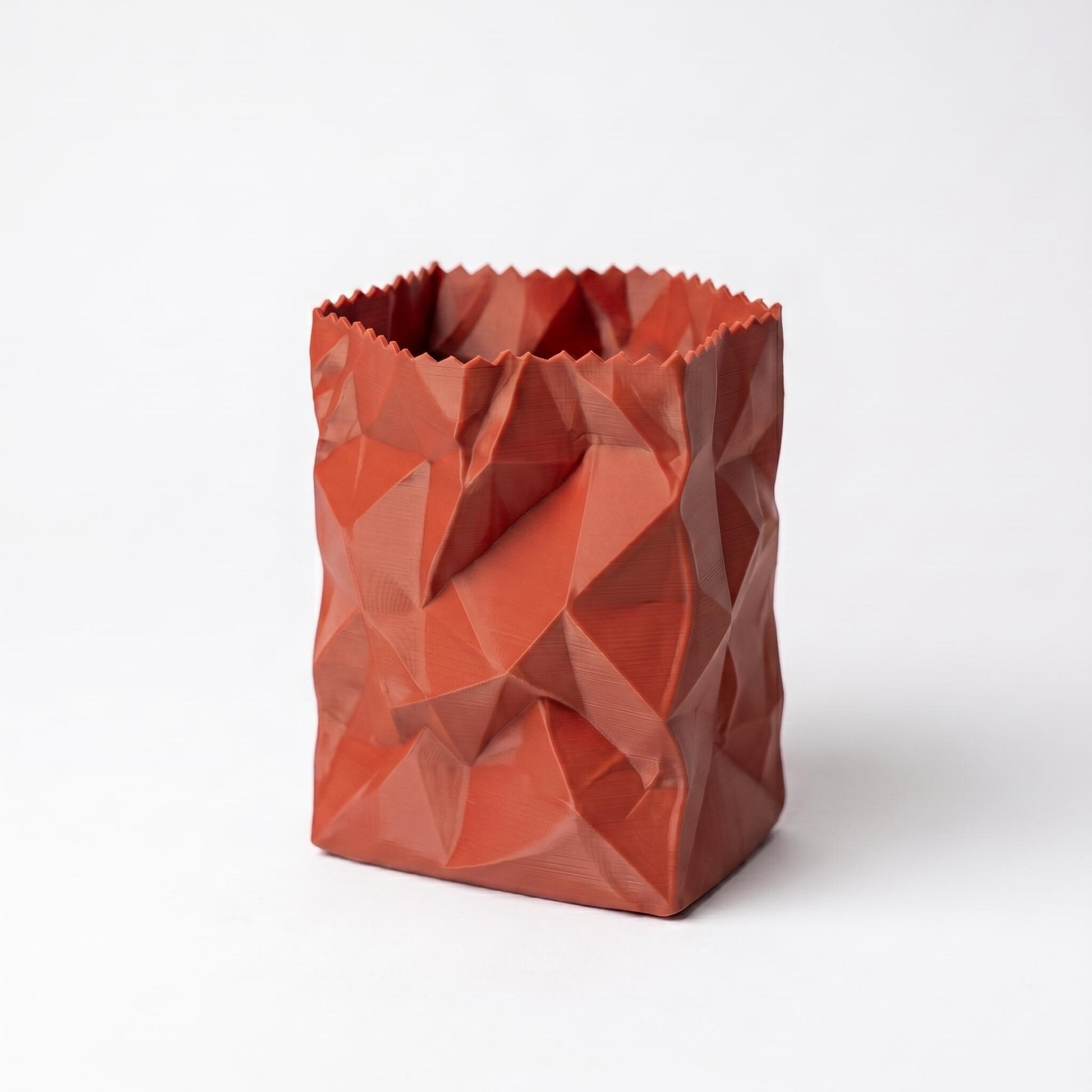 Roter 3D-gedruckter Stiftehalter im zerknüllten Papiertüten-Design mit geometrischen Facetten vor weißem Hintergrund