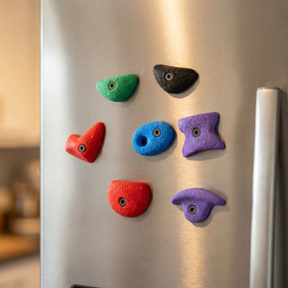 Bouldergriff-Magnete in lockerer Anordnung auf moderner Edelstahl-Kühlschranktür — minimalistischer Color-Pop als Wohn-Deko.