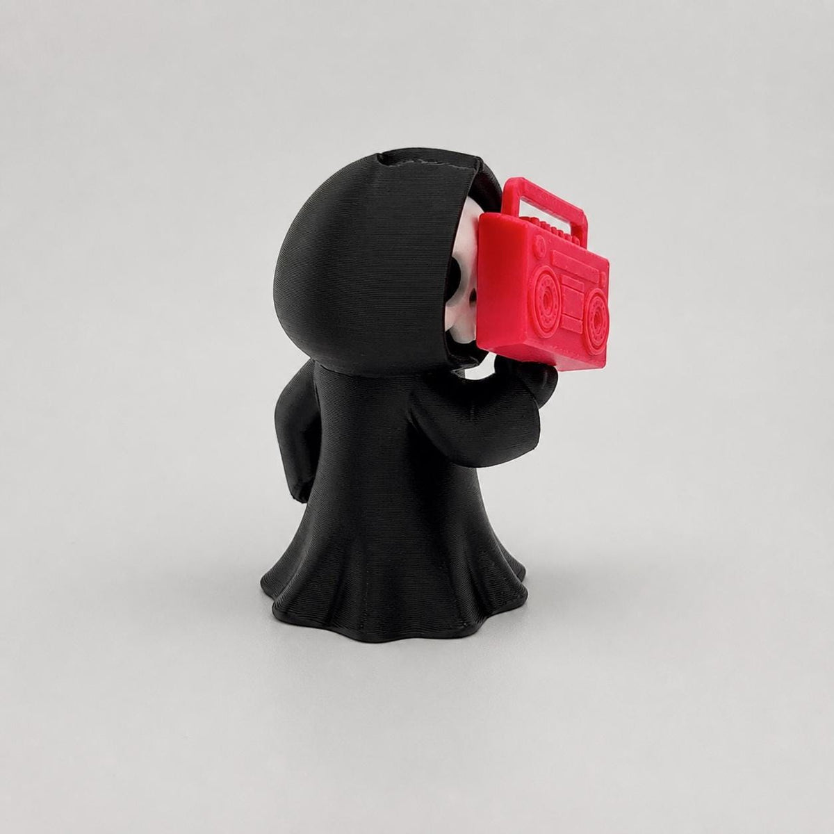 3D-gedruckte Gothic Sensenmann-Figur aus PLA mit sichtbaren feinen Druckschichten als bewusstem Teil der Oberfläche; alternative Ansicht der Boombox-Figur von schräg hinten.