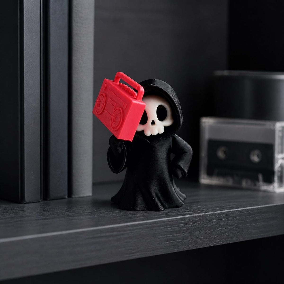 3D-gedruckte Gothic Sensenmann-Figur aus PLA mit sichtbaren feinen Druckschichten als bewusstem Teil der Oberfläche; Sensenmann mit Boombox in einer Bücherregal-Szene.
