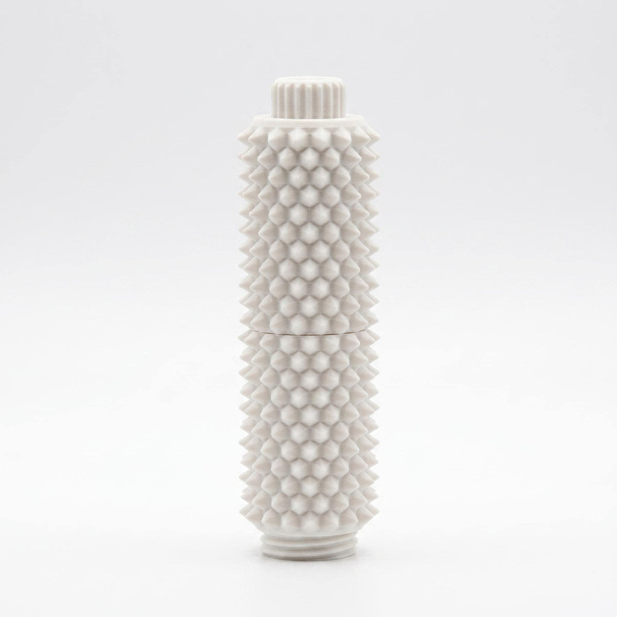 Weißes Spiky Clicker Fidget Toy steht aufrecht vor einem hellgrauen Hintergrund. Zu sehen sind der Drehknopf, die zweiteilige Form und die gleichmäßige Stachelstruktur.