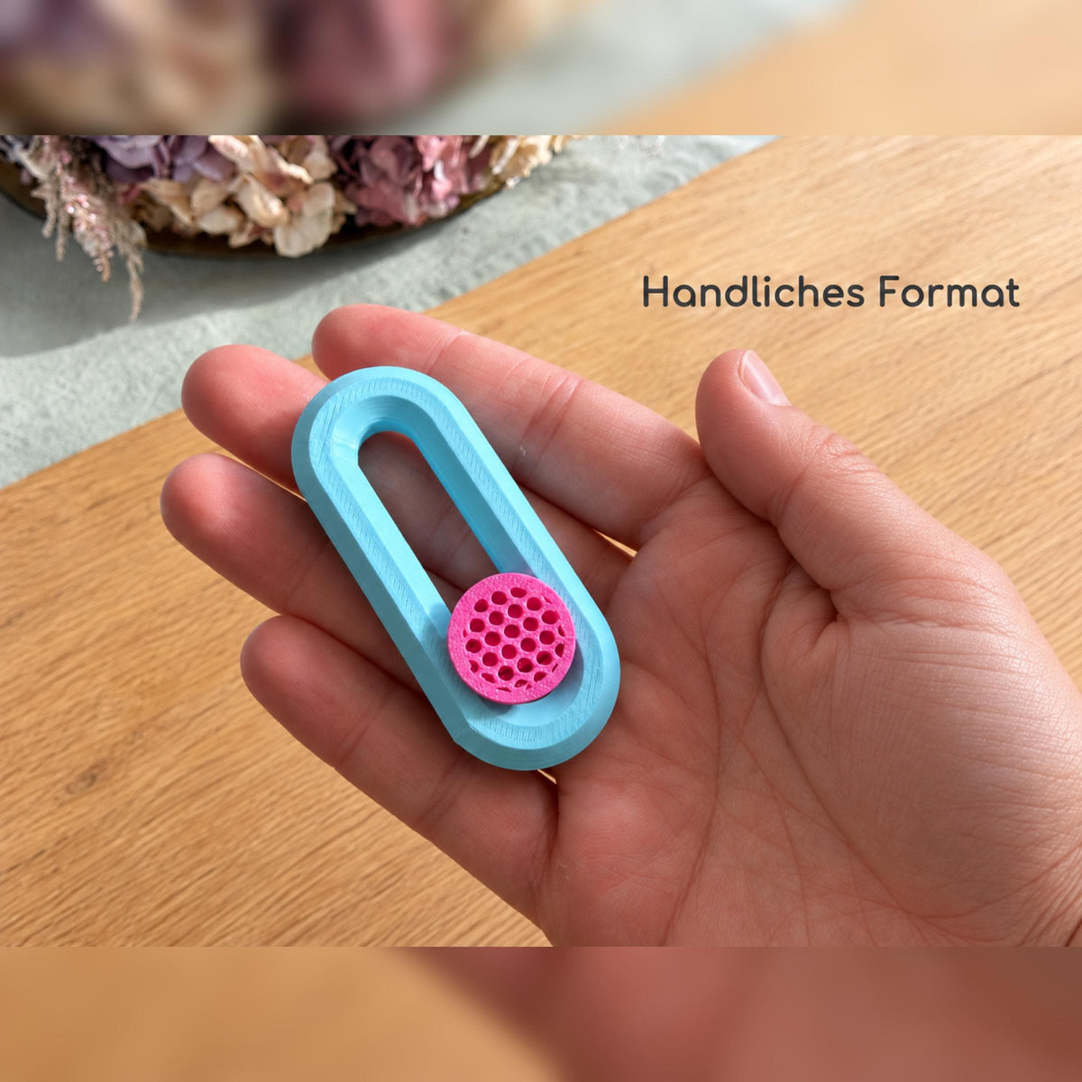 Fidget Slider in einer Hand als Größenvergleich.