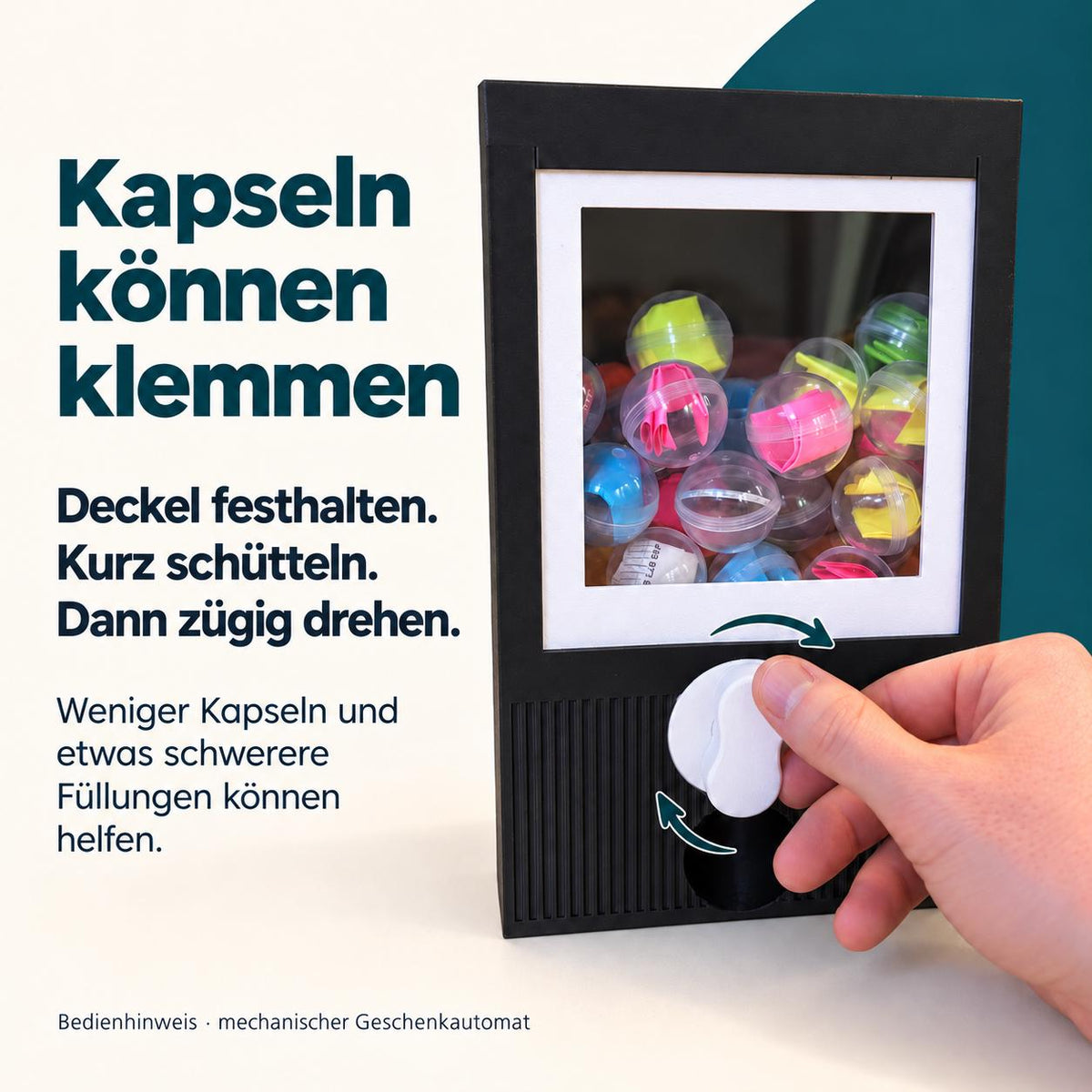 Kapseln können klemmen. Deckel festhalten, kurz schütteln, dann zügig drehen. Weniger Kapseln und etwas schwerere Füllungen können helfen. Schwarzer mechanischer Geschenkautomat mit weißem Rahmen und Drehknopf.