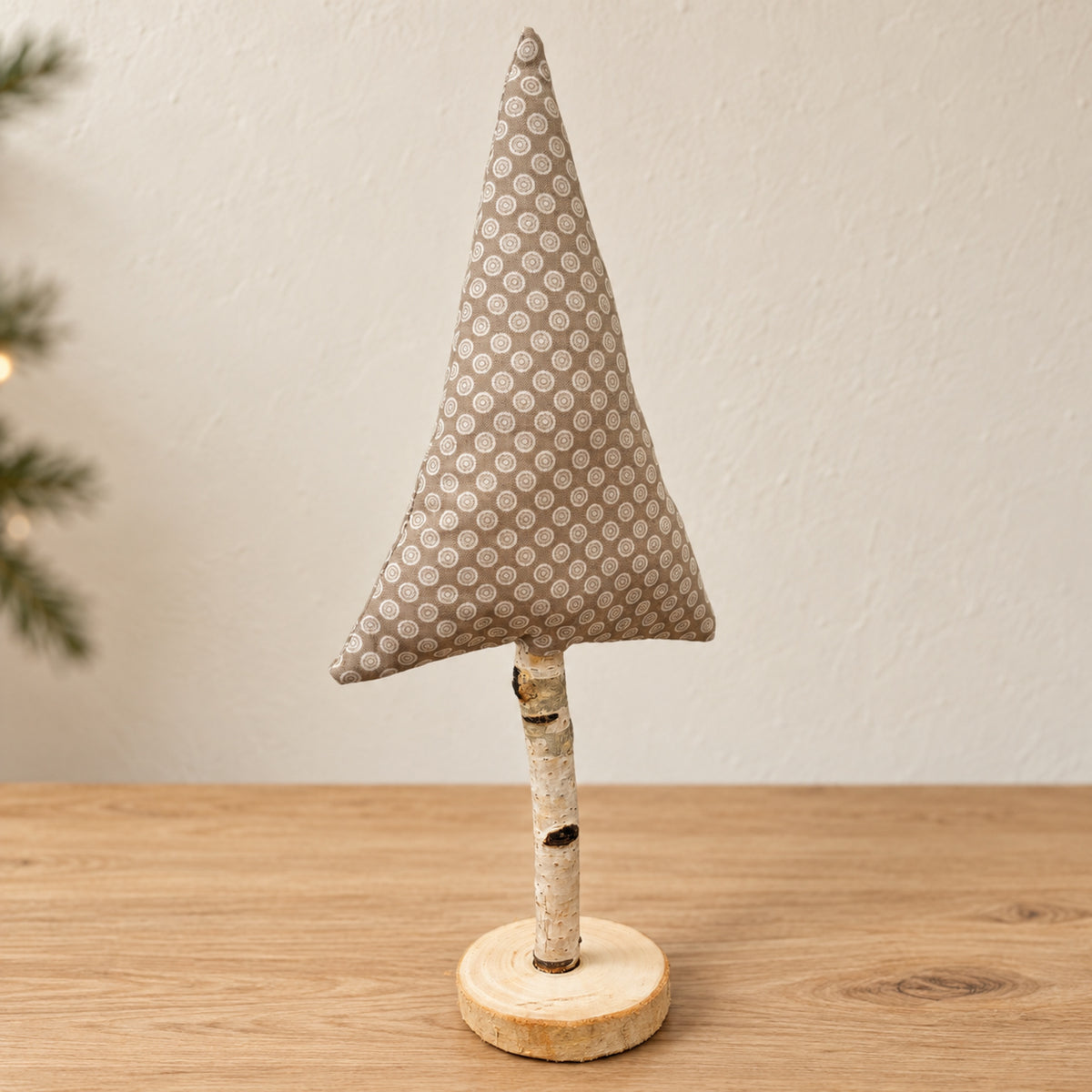 Handgenähter Stoff-Tannenbaum in Beige mit Weißmuster auf Naturast und echter Holzscheibe.