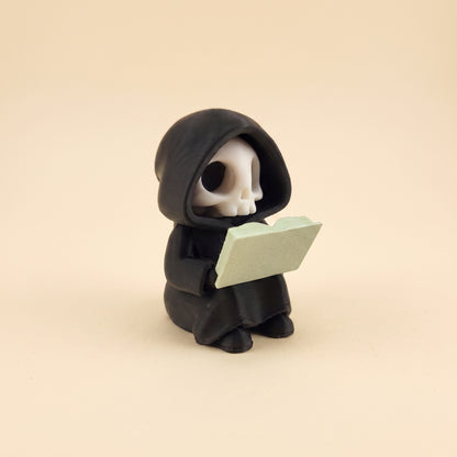 Lesender Sensenmann auf Buch – Figur fürs Bücherregal – Produktfoto auf Creme-Hintergrund