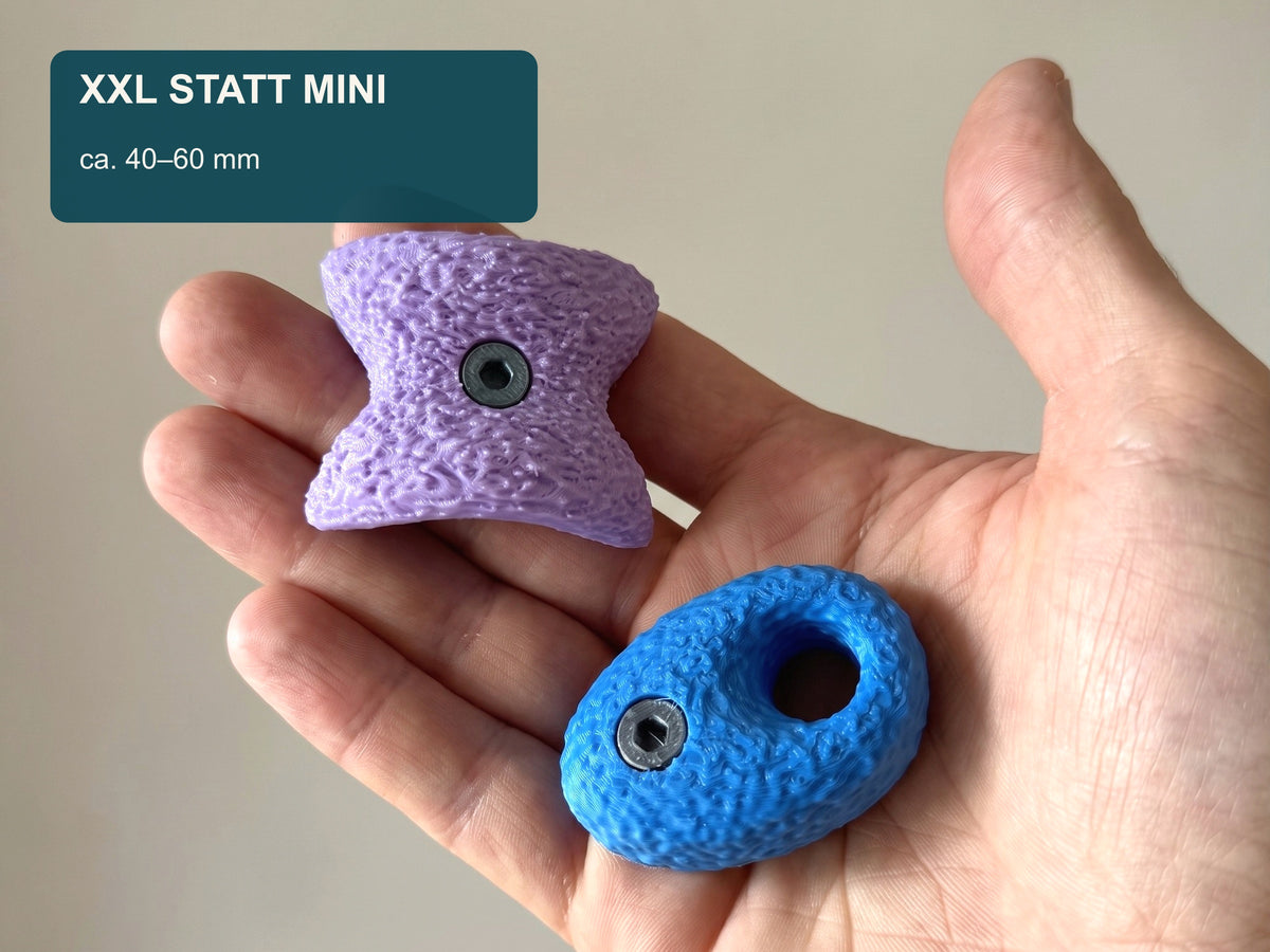 Zwei große Bouldergriff-Magnete in einer Hand als Größenvergleich; jeder Griff misst etwa 40 bis 60 Millimeter.