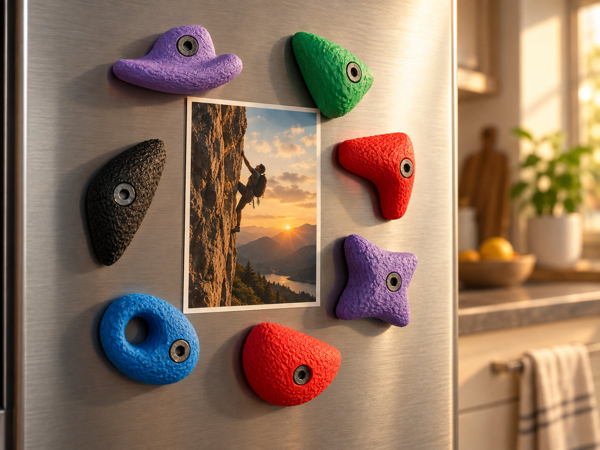 Sieben große bunte Bouldergriff-Magnete auf einer Edelstahl-Kühlschranktür halten ein Outdoor-Kletterfoto.